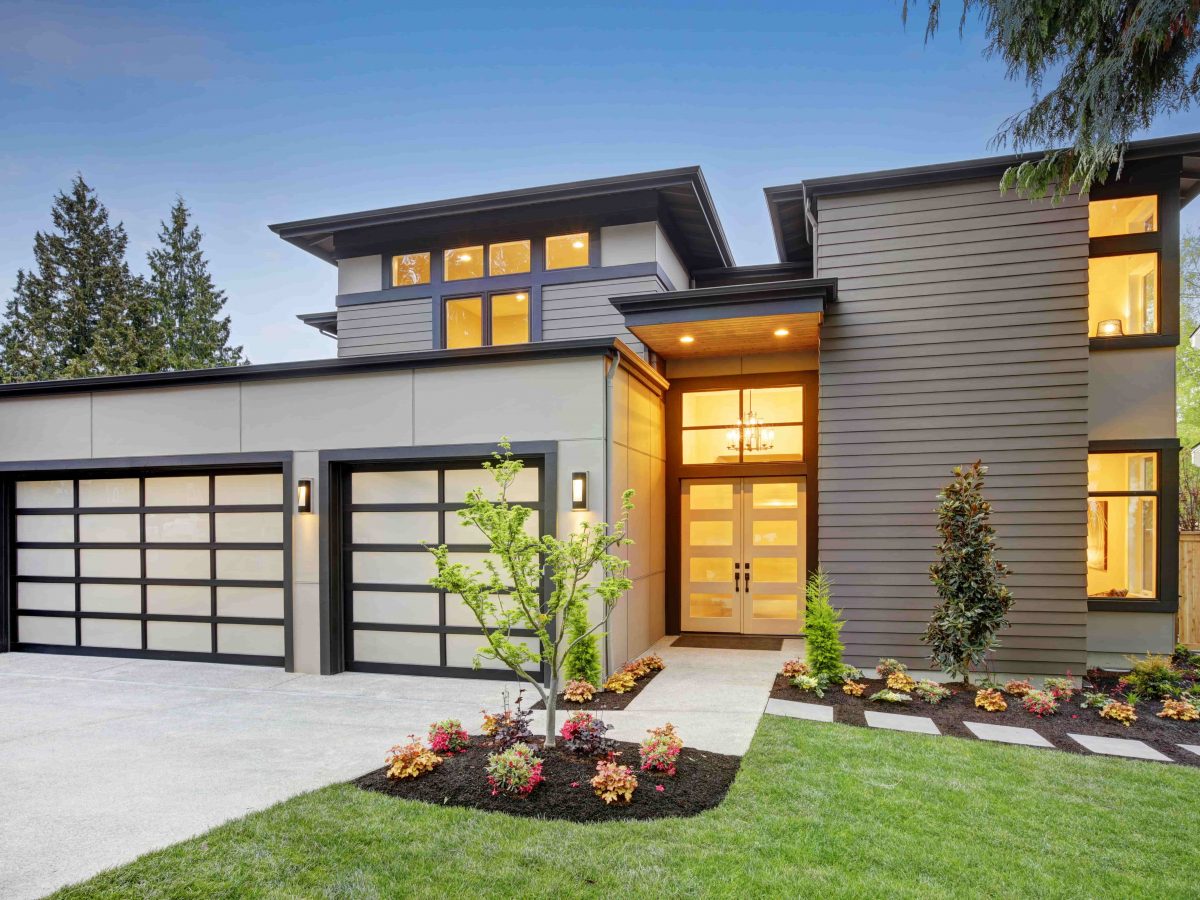 Contemporary custom home exterior at dusk with glass garage doors